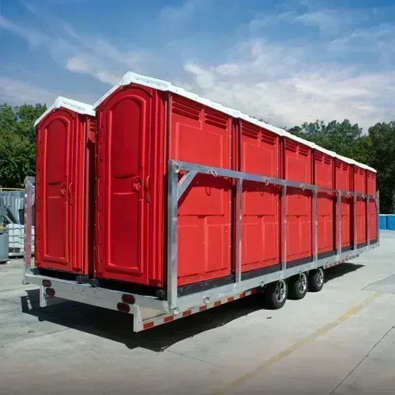 Trailer carrying multiple red portable restrooms outdoors on concrete surface