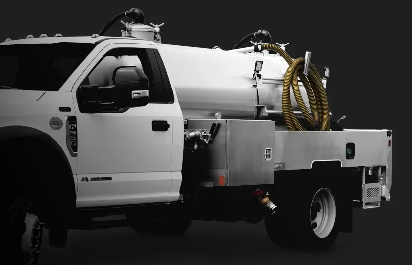 White vacuum service truck with yellow hoses coiled on tank against dark background