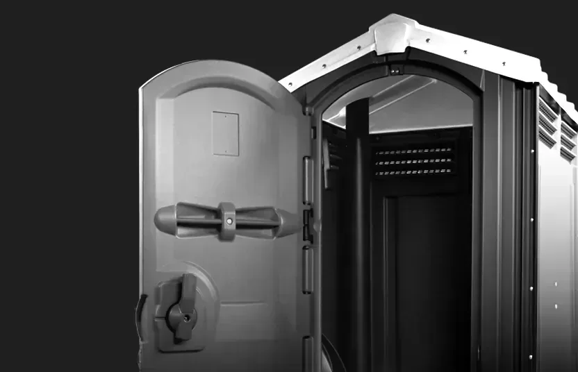 Partially open portable restroom door showing interior with ventilation panels against black background