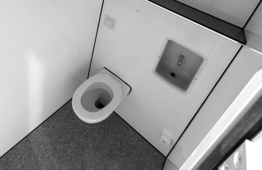 A minimalist restroom with a white toilet and a handwashing station in the corner.