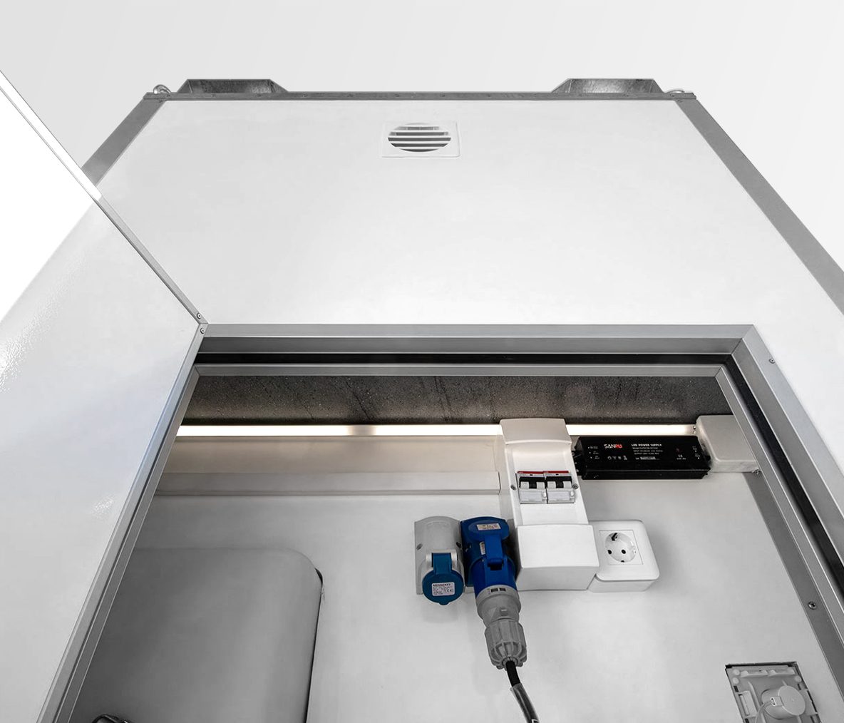 Interior of a utility enclosure with electrical outlets, a circuit breaker, and tools mounted on a