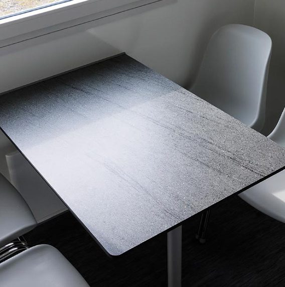 A sleek black table with a textured surface, surrounded by white chairs.