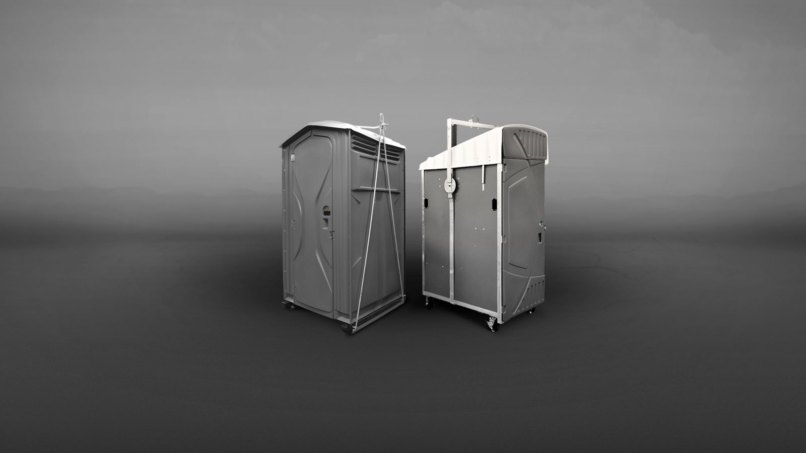 Two gray portable restrooms positioned side by side on a plain background.
